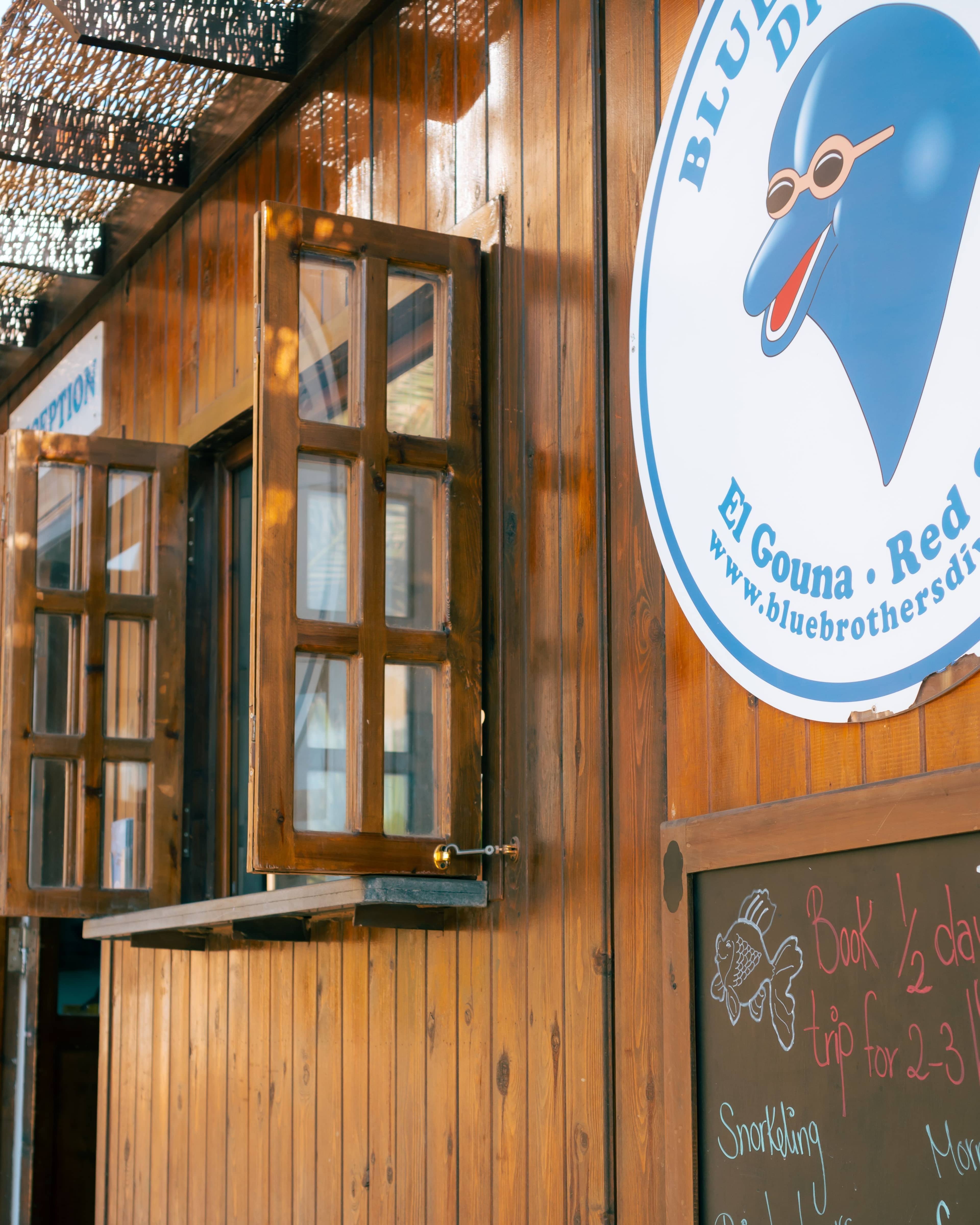 Wooden building with open windows and a round "Blue Brothers Diving" logo on the right.