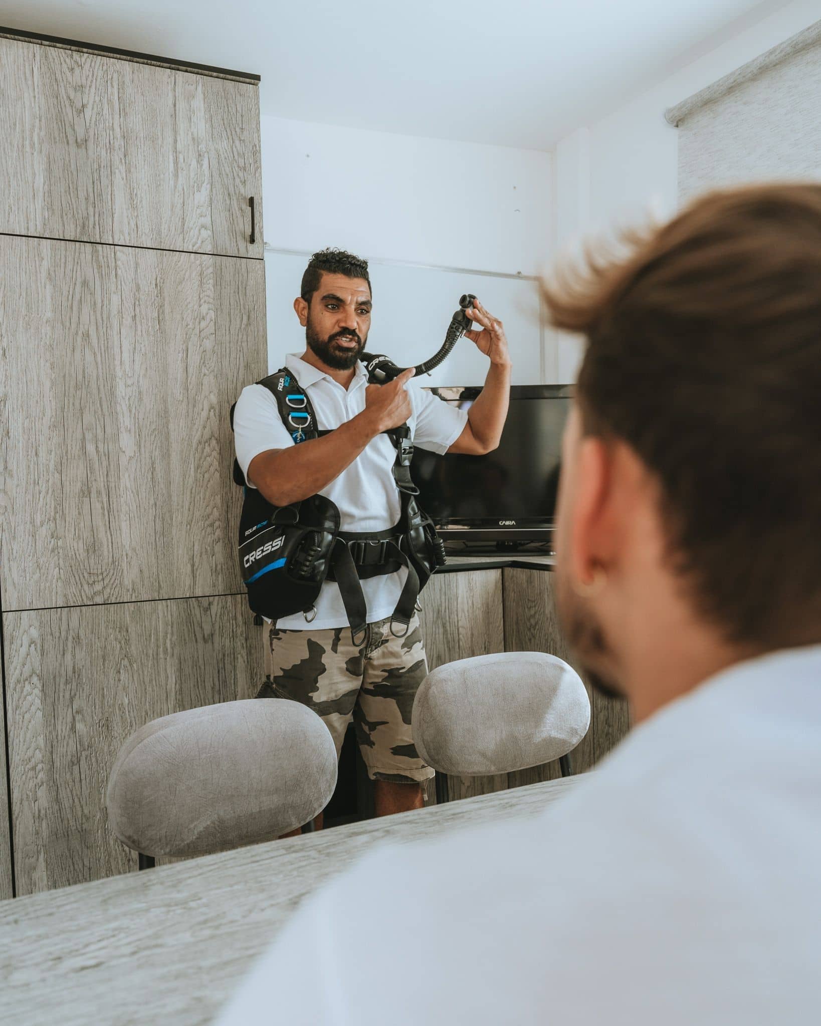 Man adjusting a black harness and looking at his reflection in a mirror.
