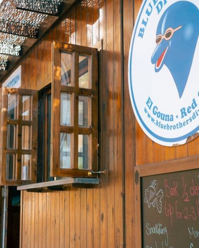 Wooden building with open windows and a round "Blue Brothers Diving" logo on the right.