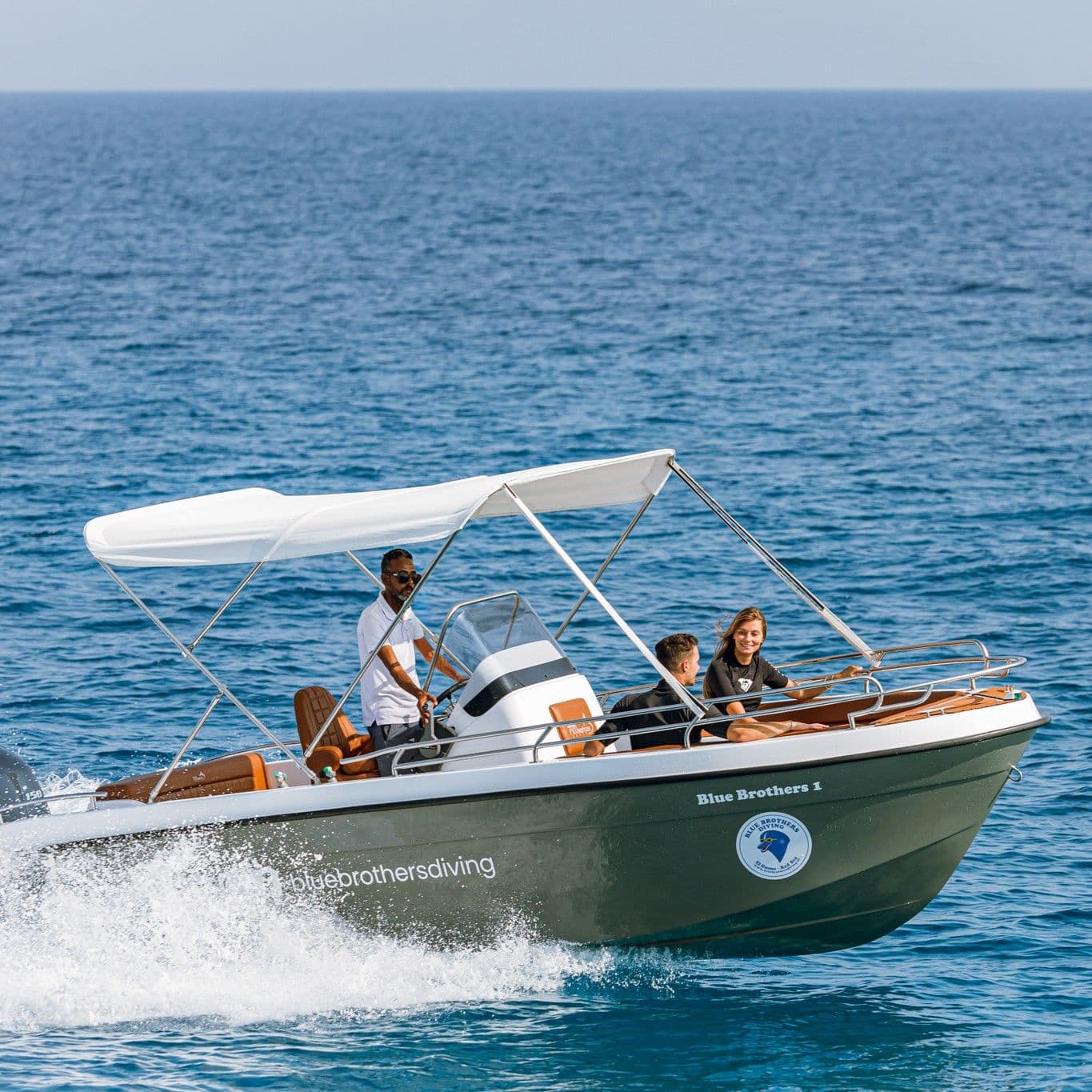 Family enjoying a boat ride on calm blue ocean waters under a white canopy.